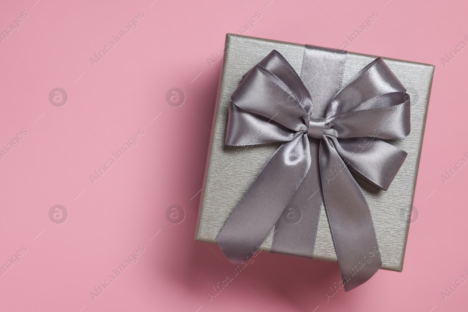 Photo of Gift box with bow on dusty pink background, top view