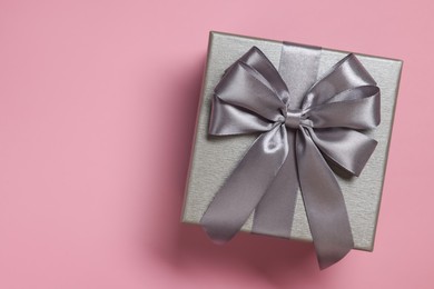 Photo of Gift box with bow on dusty pink background, top view