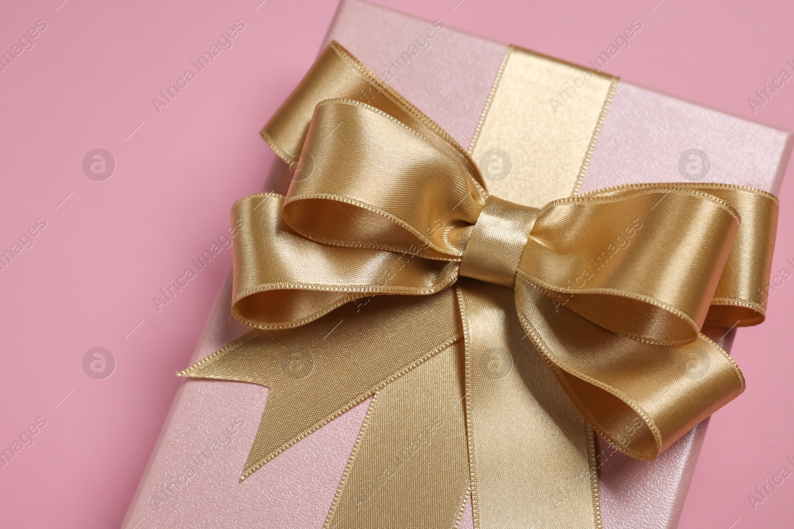 Photo of Gift box with bow on dusty pink background, closeup