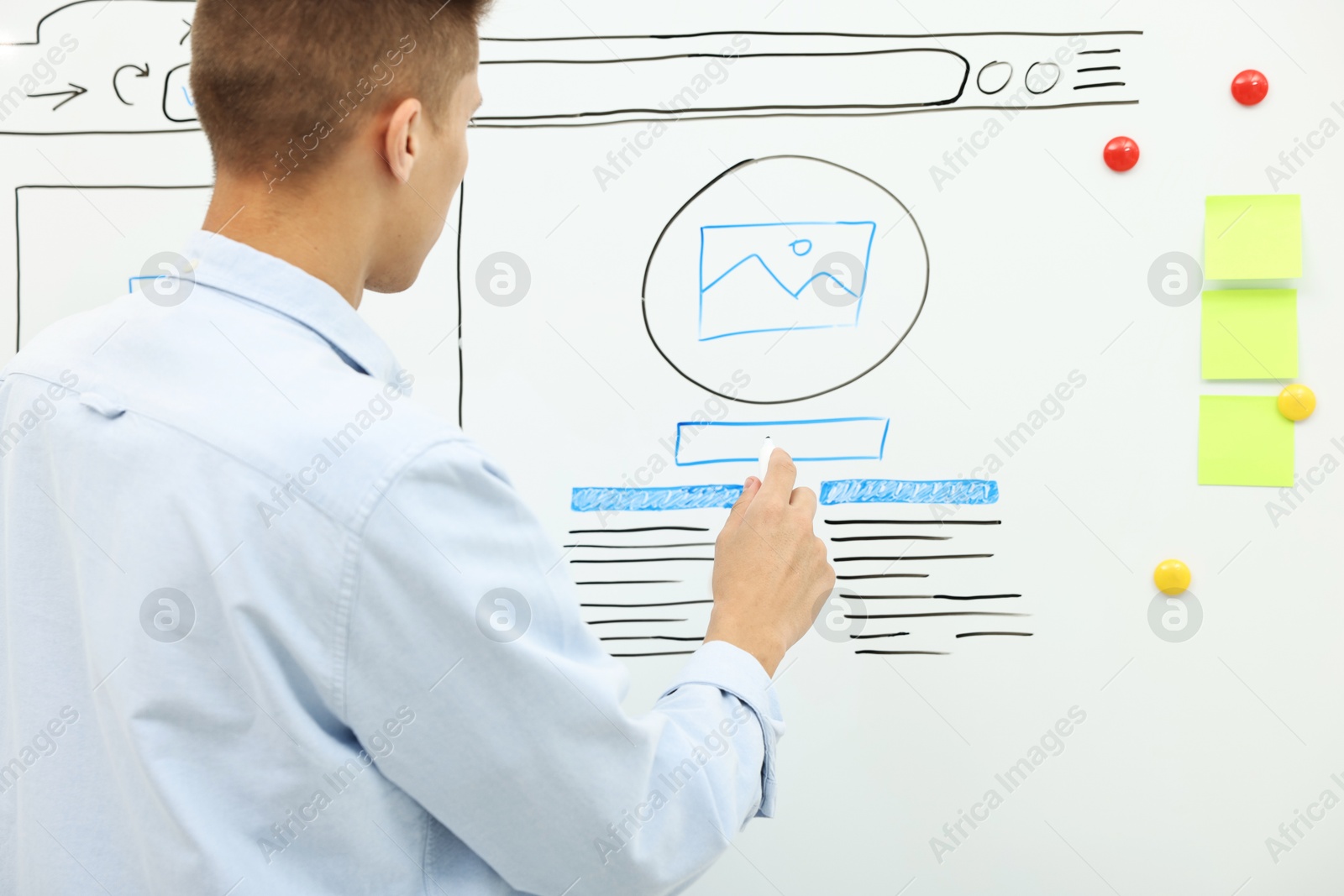 Photo of Developing UI design. Man drawing website wireframe on whiteboard indoors, back view