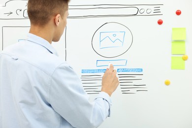 Developing UI design. Man drawing website wireframe on whiteboard indoors, back view