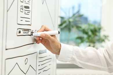 Photo of Developing UI design. Woman drawing website wireframe on whiteboard indoors, closeup