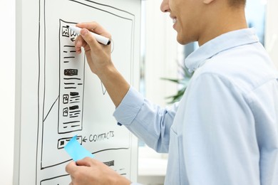 Developing UI design. Man drawing website wireframe on whiteboard indoors, closeup