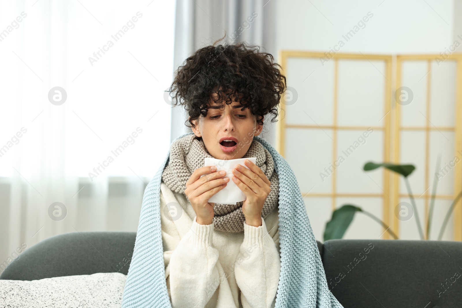 Photo of Cold symptom. Young woman with tissue at home