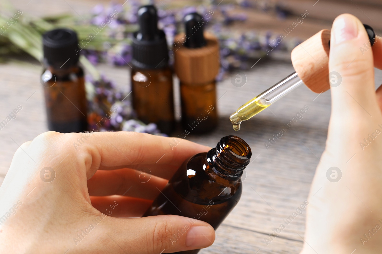 Photo of Woman using essential oil at wooden table, closeup