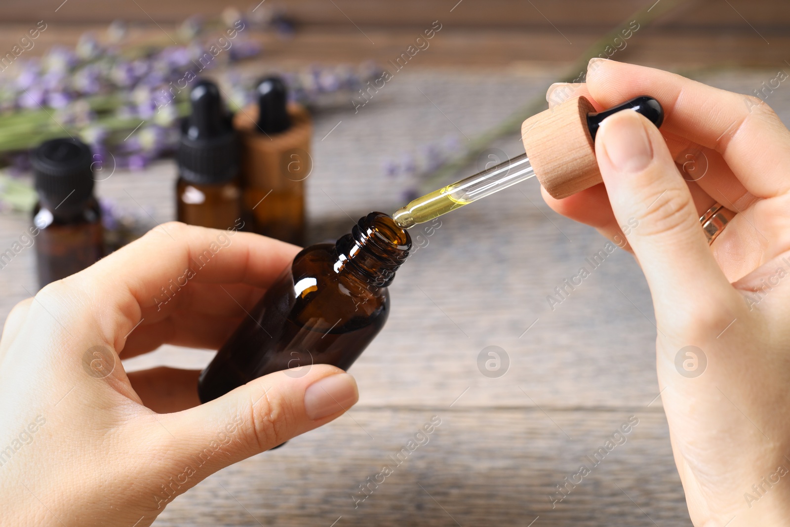 Photo of Woman using essential oil at wooden table, closeup