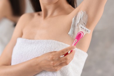 Photo of Woman shaving armpit indoors, closeup. Depilation procedure