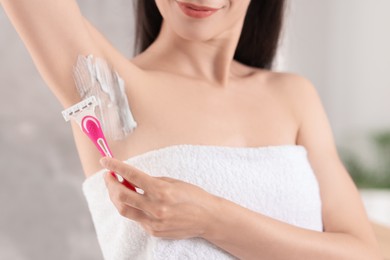 Photo of Woman shaving armpit indoors, closeup. Depilation procedure