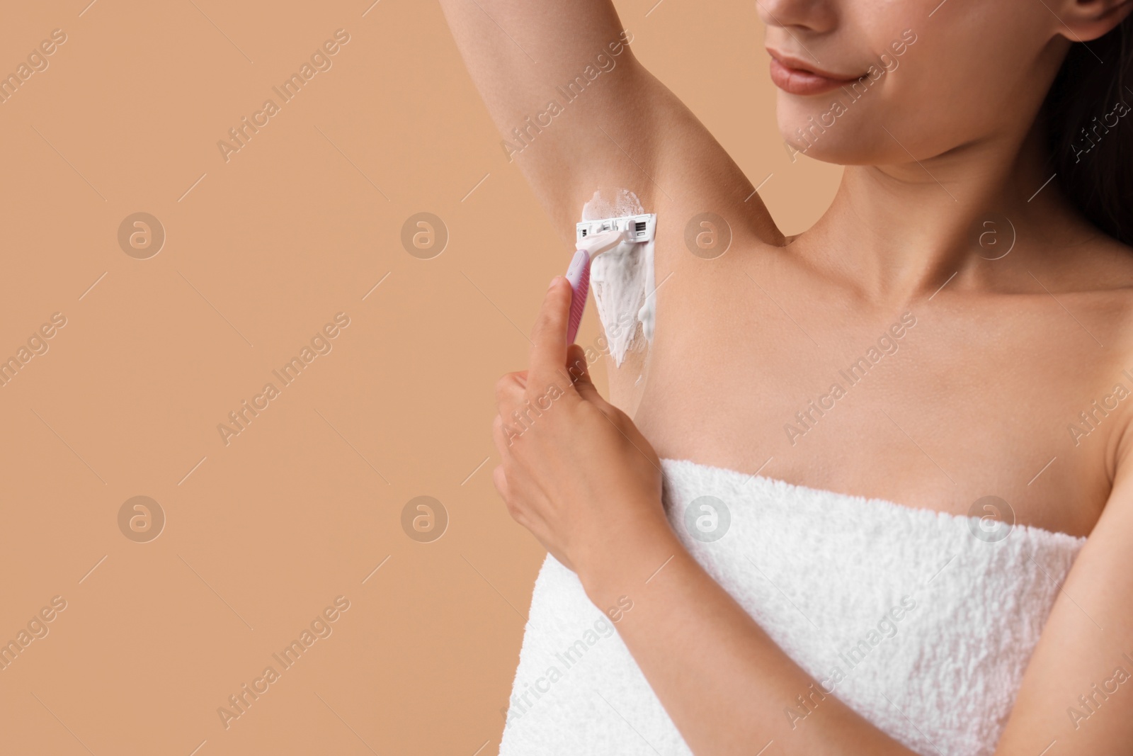 Photo of Woman shaving armpit on beige background, closeup. Space for text