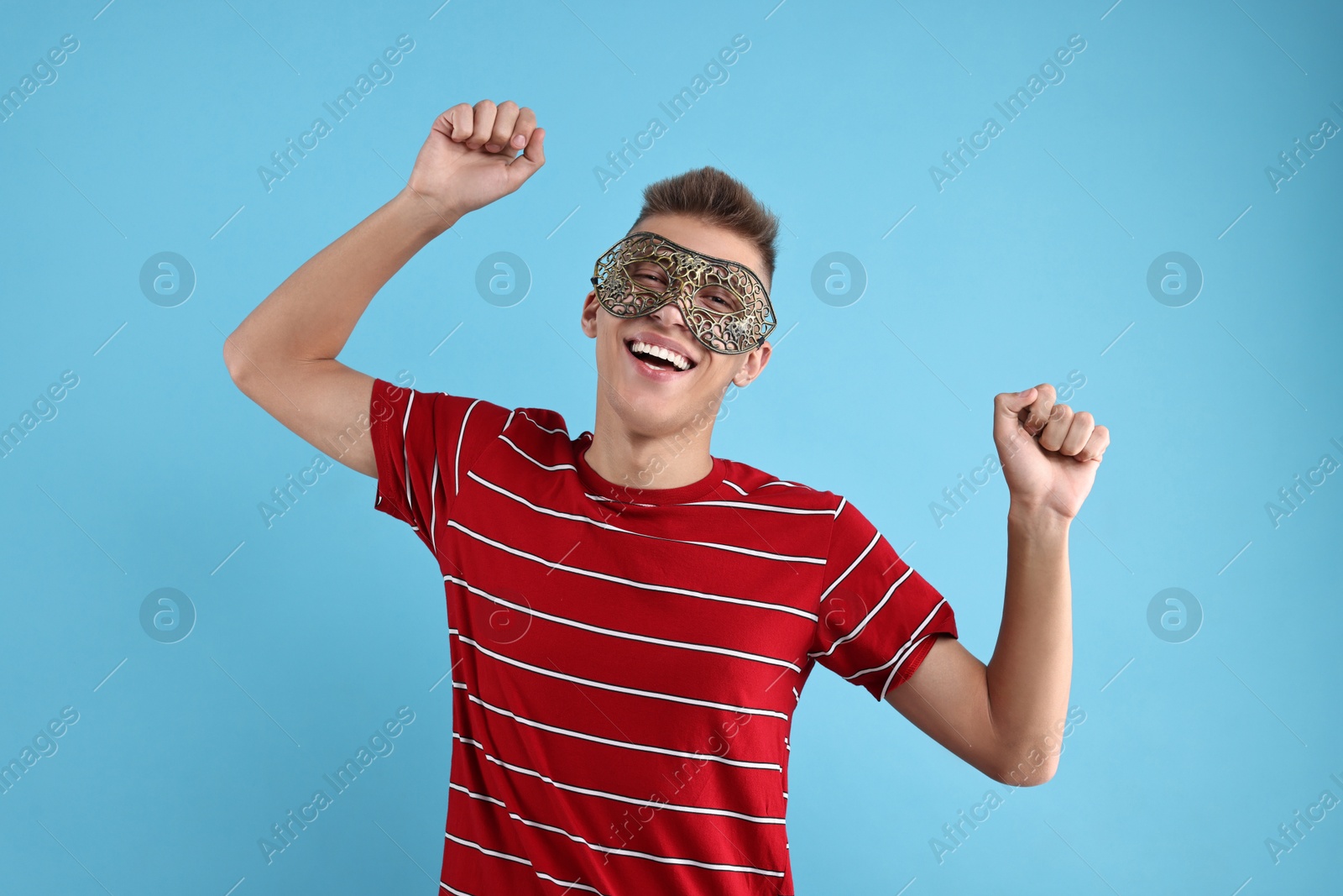 Photo of Charming young man wearing carnival mask on light blue background