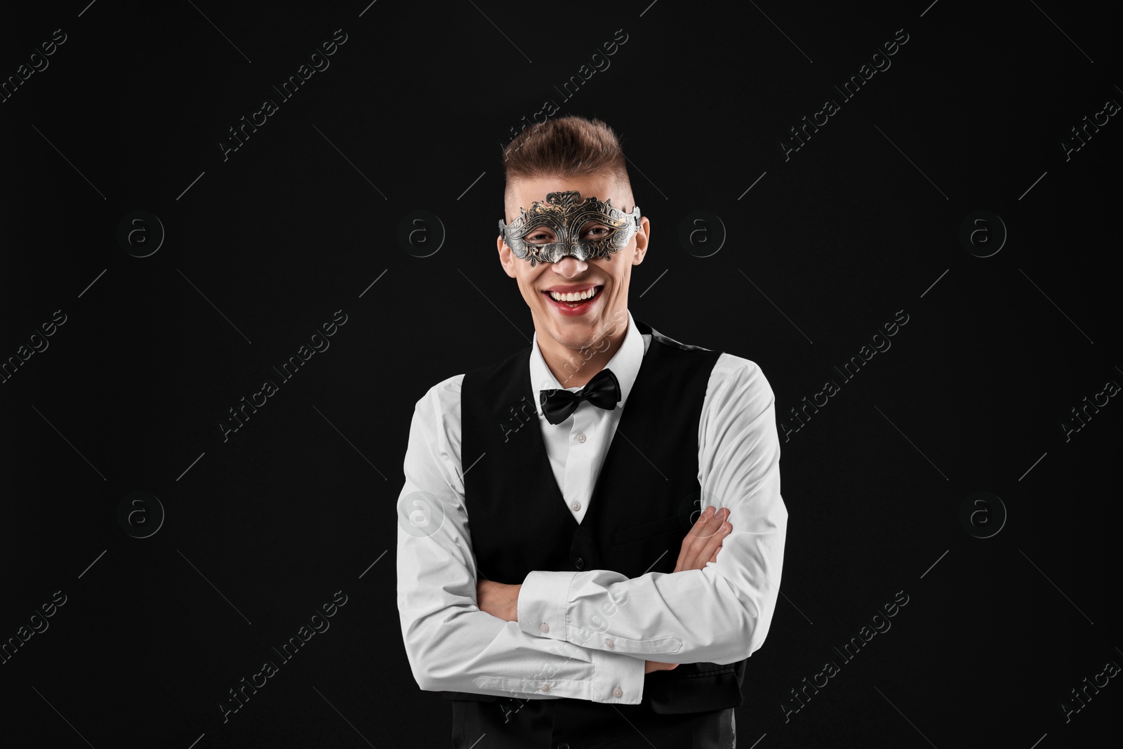 Photo of Charming young man wearing carnival mask on black background