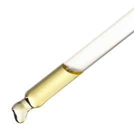 Essential oil dripping from pipette against white background