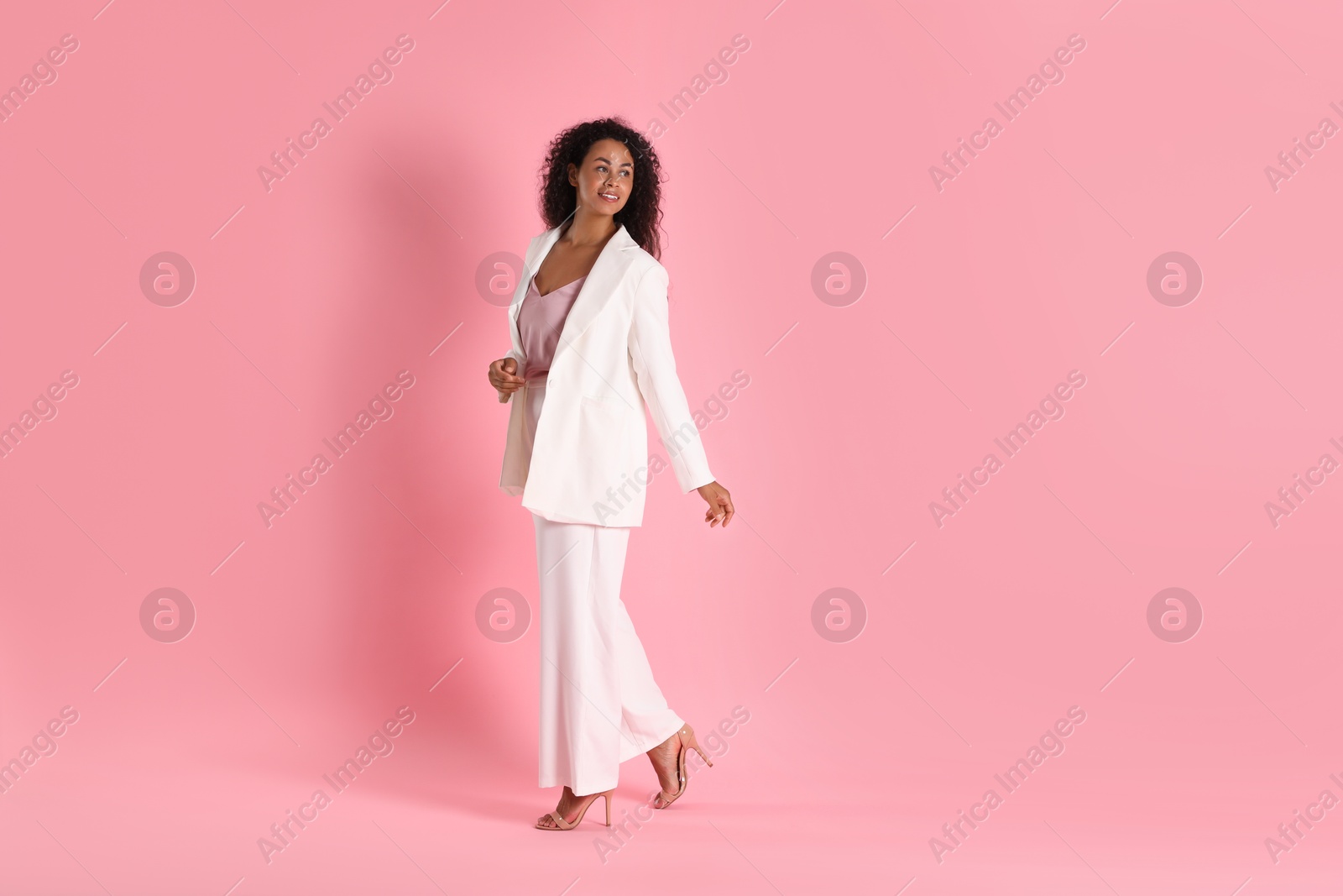 Photo of Beautiful woman in stylish suit on pink background, space for text