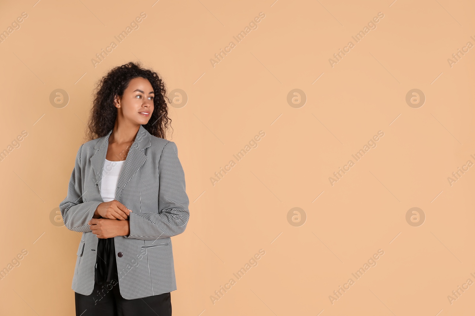 Photo of Beautiful woman in stylish jacket on beige background, space for text