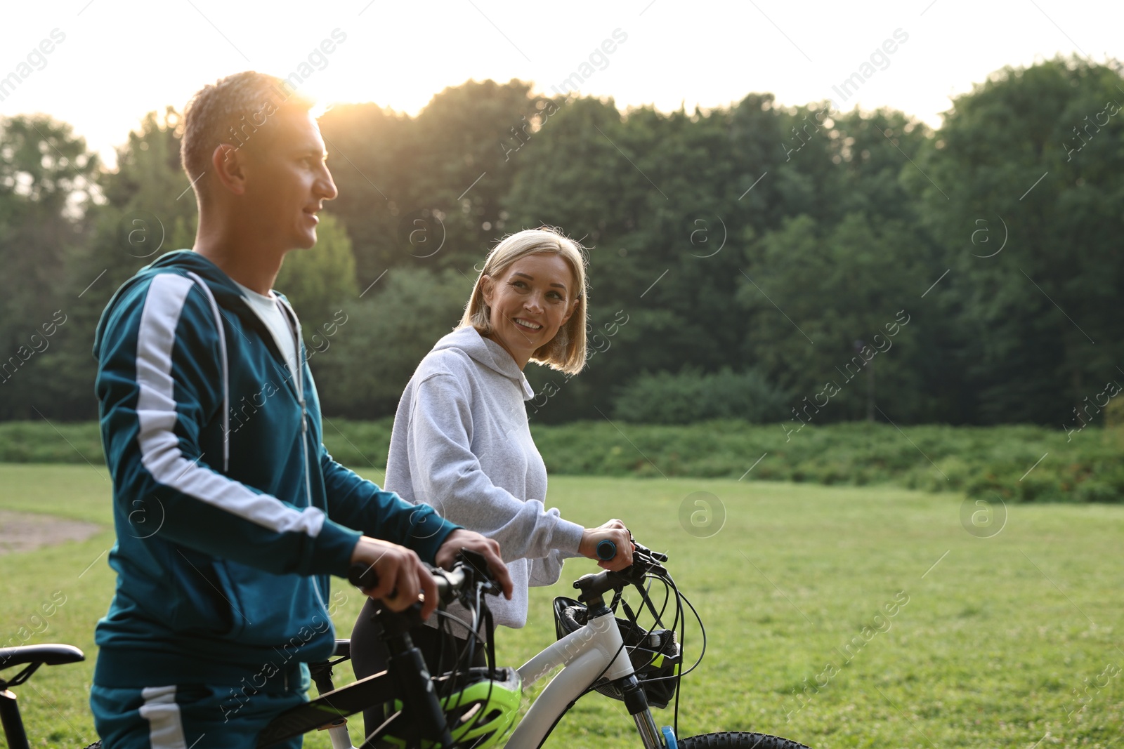 Photo of Happy couple riding bicycles in park. Healthy lifestyle