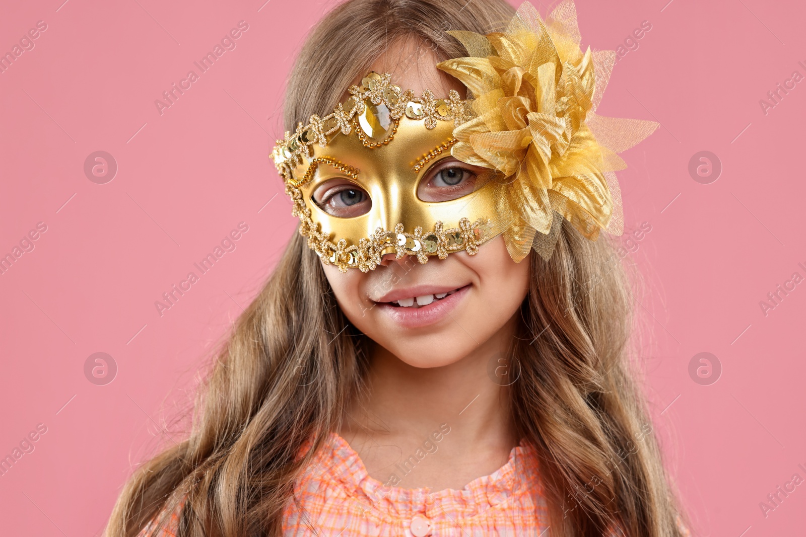 Photo of Cute girl wearing carnival mask on pink background