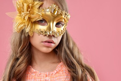 Cute girl wearing carnival mask on pink background, space for text