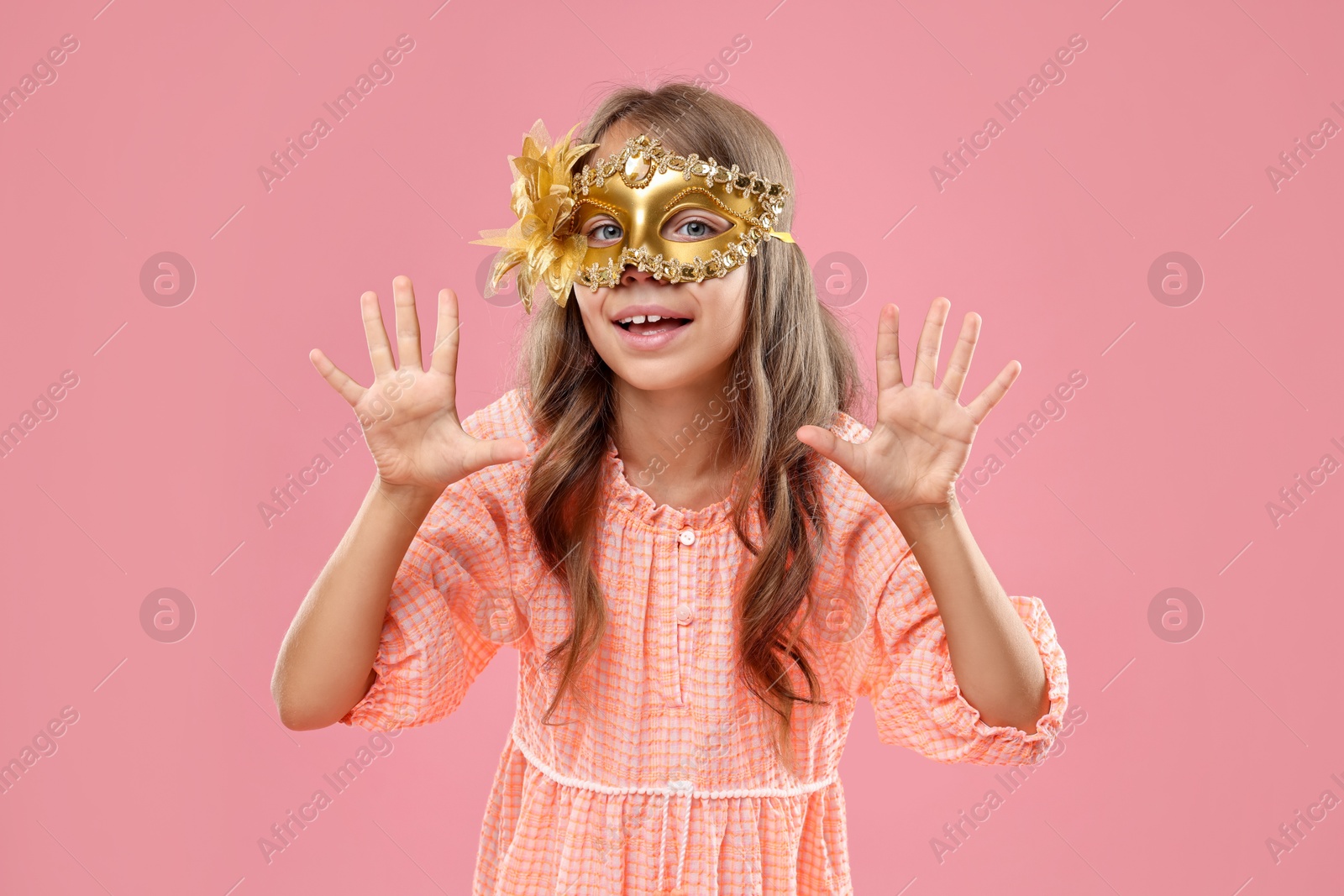 Photo of Cute girl wearing carnival mask on pink background