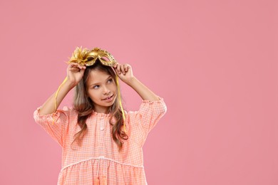 Cute girl wearing carnival mask on pink background, space for text