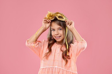 Photo of Cute girl wearing carnival mask on pink background