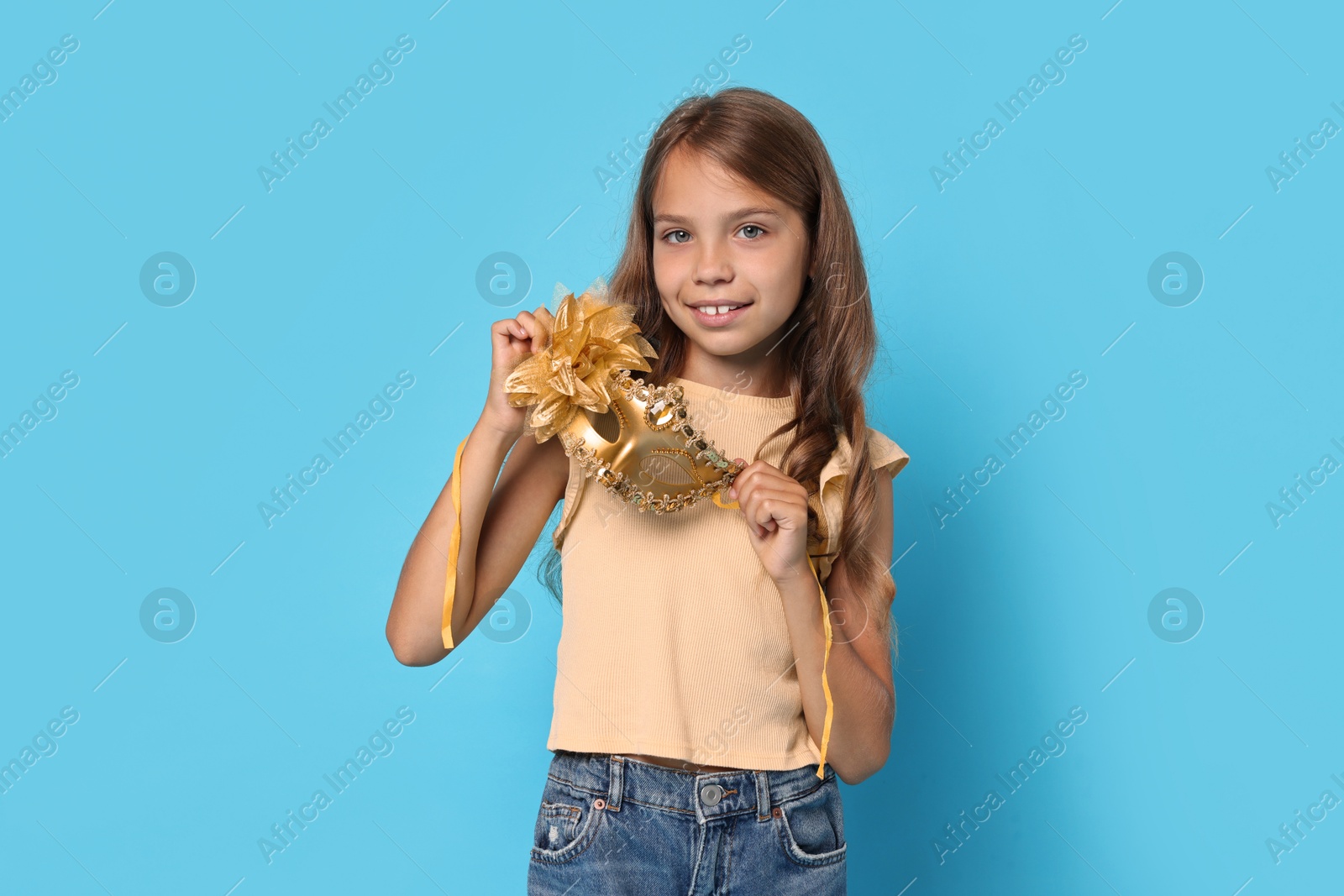 Photo of Happy girl with carnival mask on light blue background