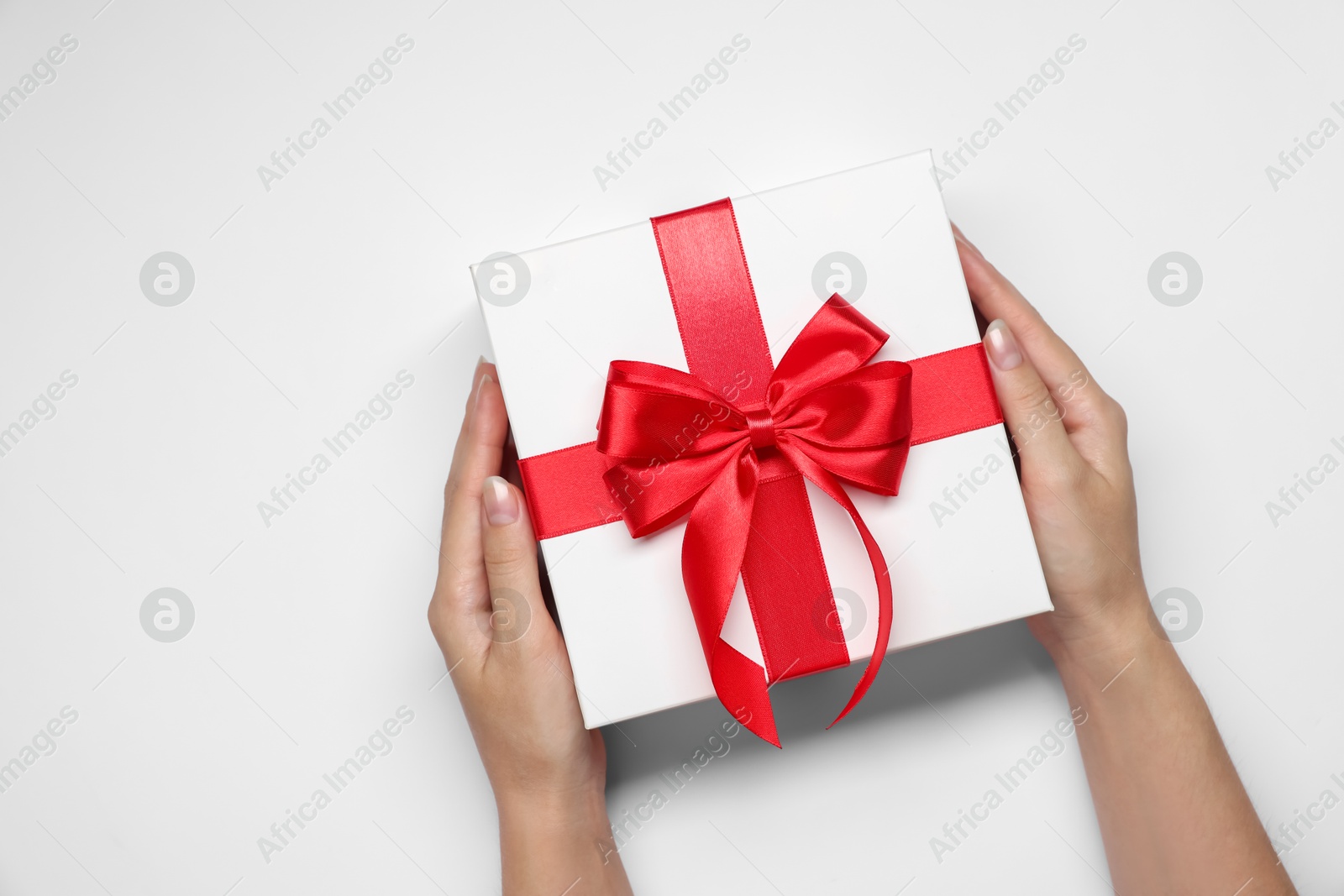 Photo of Woman holding gift box with bow on white background, top view