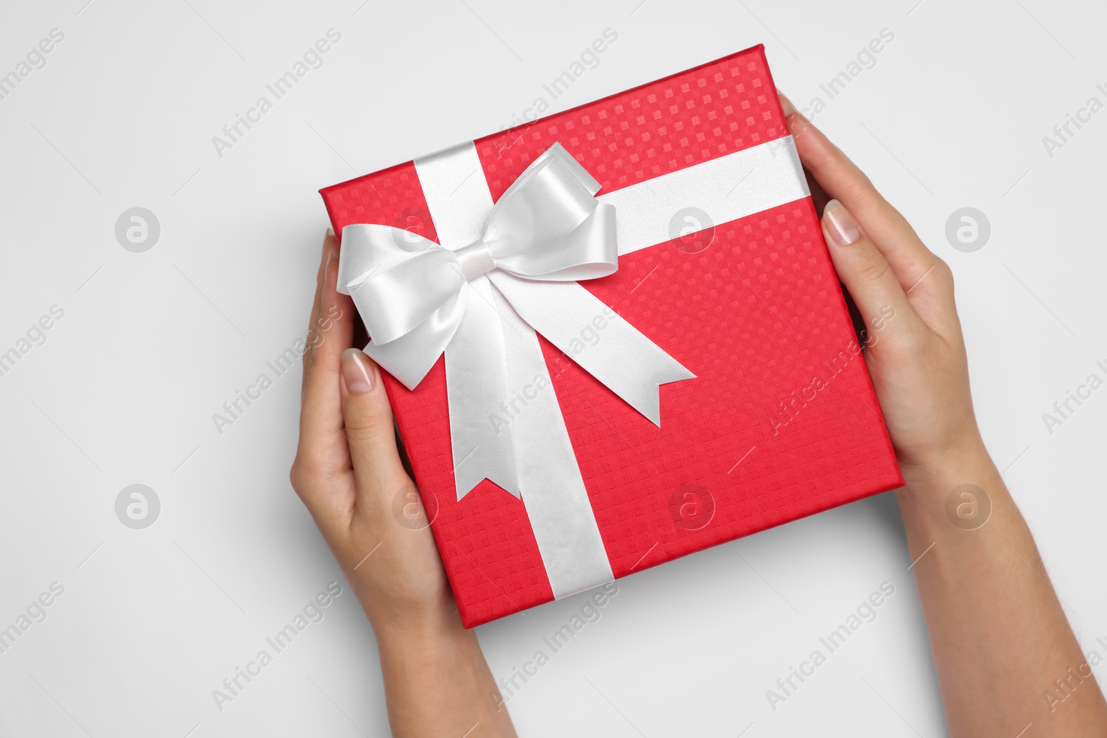 Photo of Woman holding gift box with bow on white background, top view