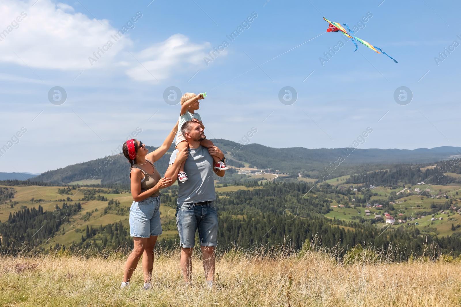 Photo of Happy family flying kite at field under blue sky