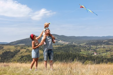 Happy family flying kite at field under blue sky