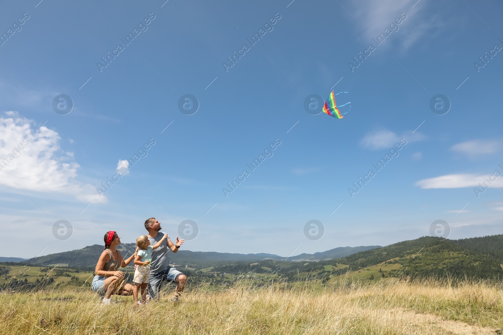 Photo of Family flying kite at field under blue sky