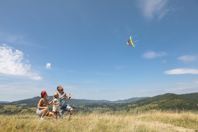 Photo of Family flying kite at field under blue sky