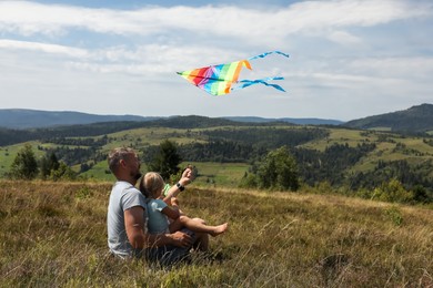 Father with daughter flying kite at field