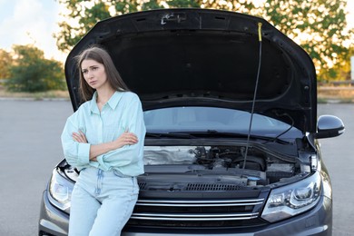 Photo of Stressed woman standing near broken car outdoors