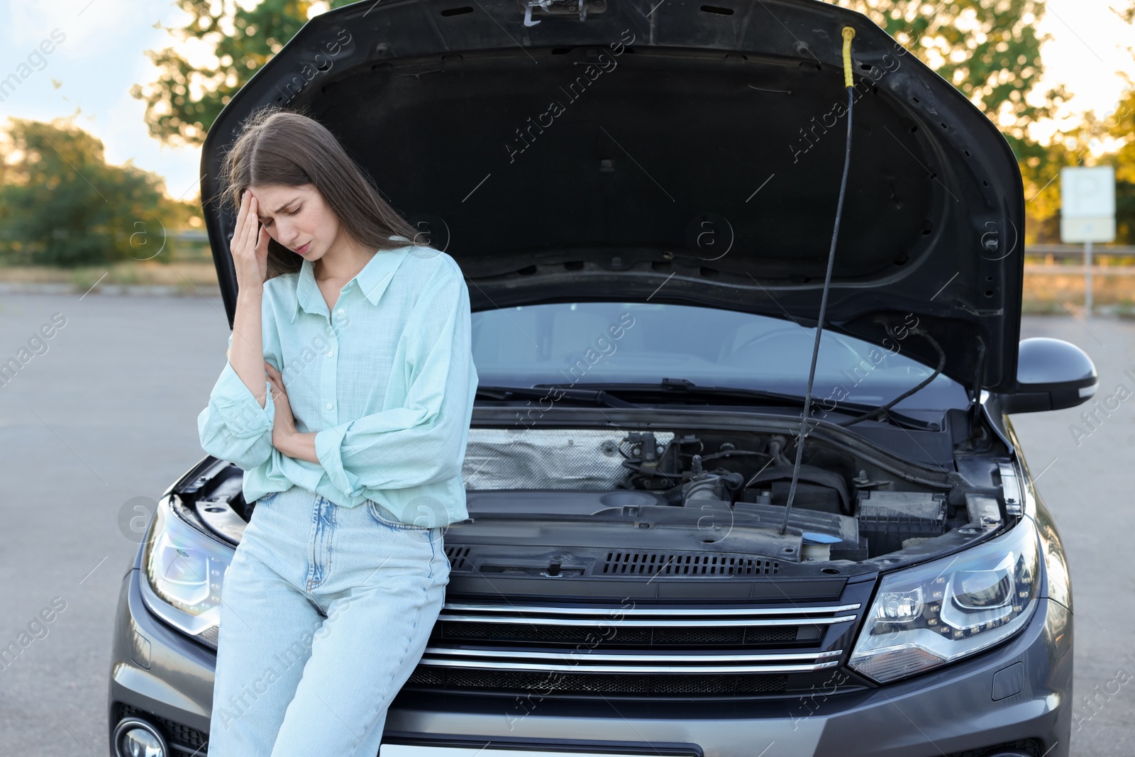 Photo of Stressed woman standing near broken car outdoors