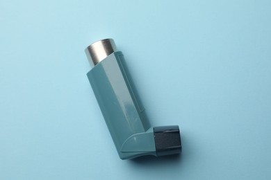 Asthma inhaler on light blue background, top view