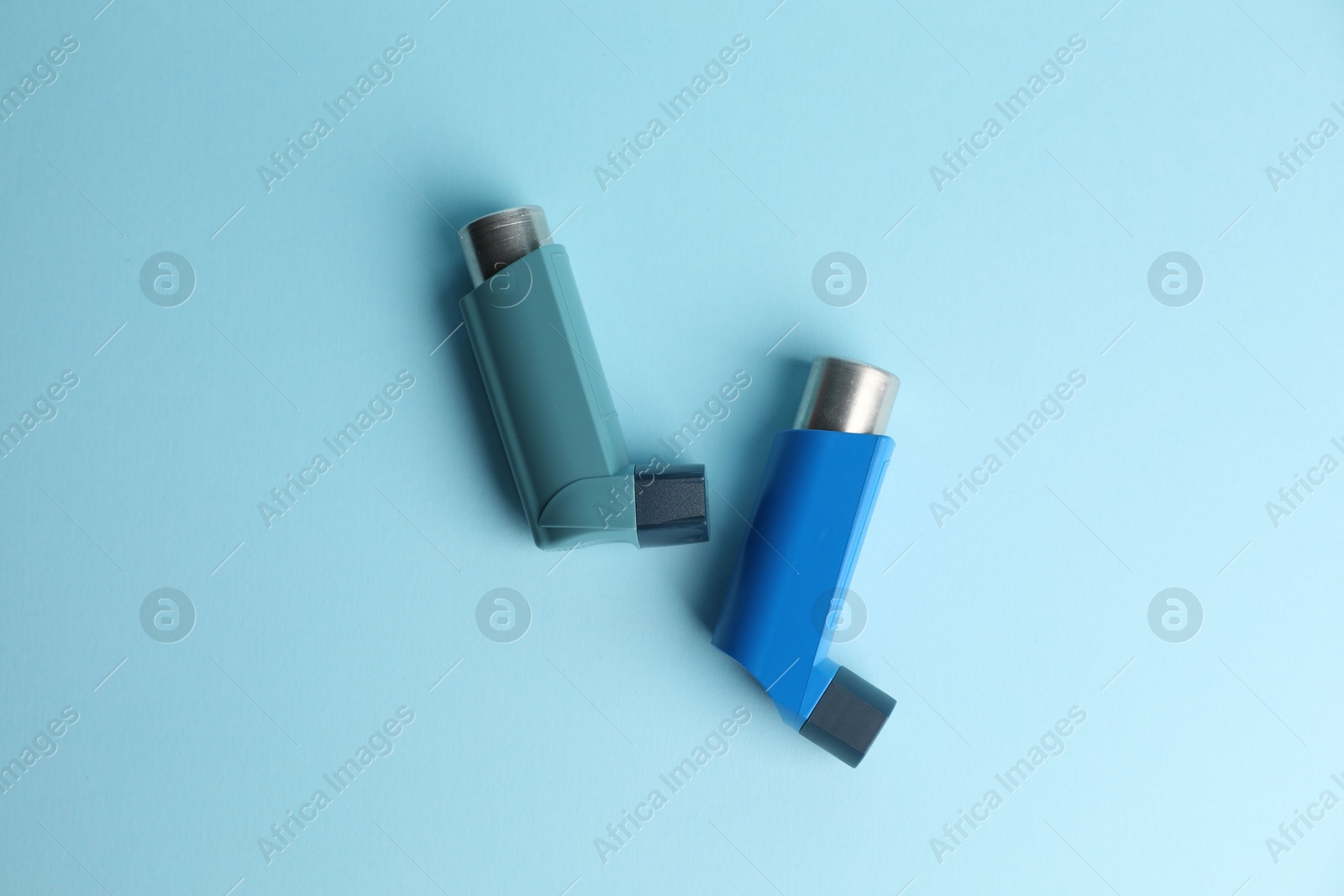 Photo of Asthma inhalers on light blue background, top view