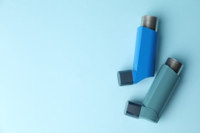 Photo of Asthma inhalers on light blue background, top view. Space for text