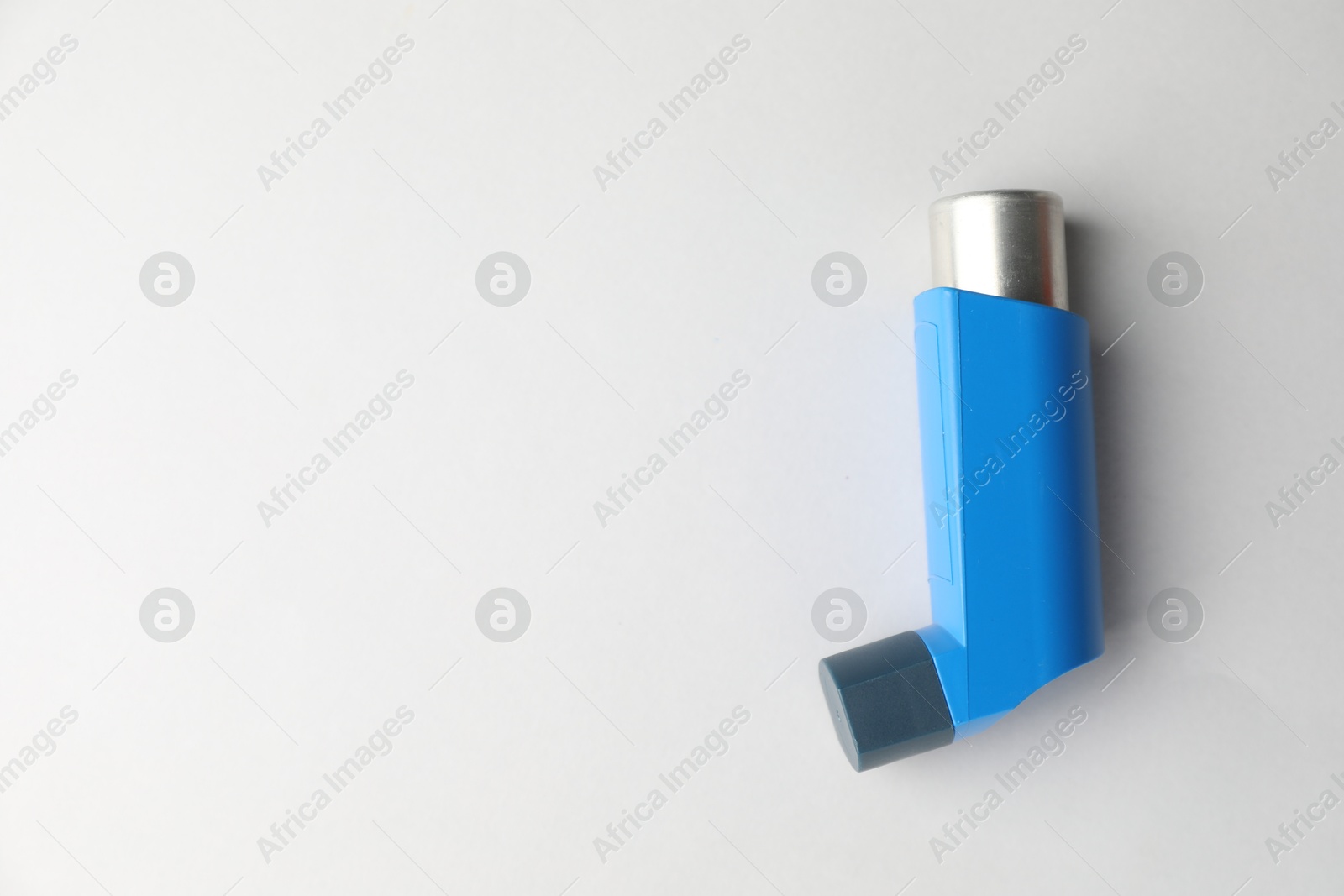 Photo of Asthma inhaler on light grey background, top view. Space for text