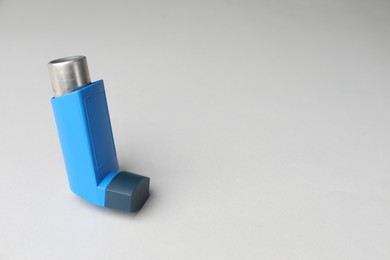 Asthma inhaler on light grey background, space for text