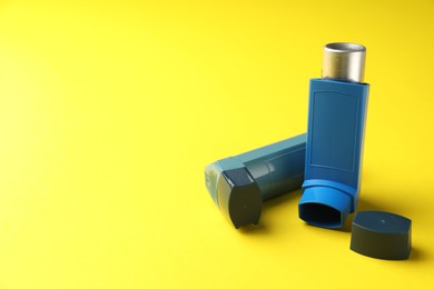 Photo of Two asthma inhalers on yellow background, space for text