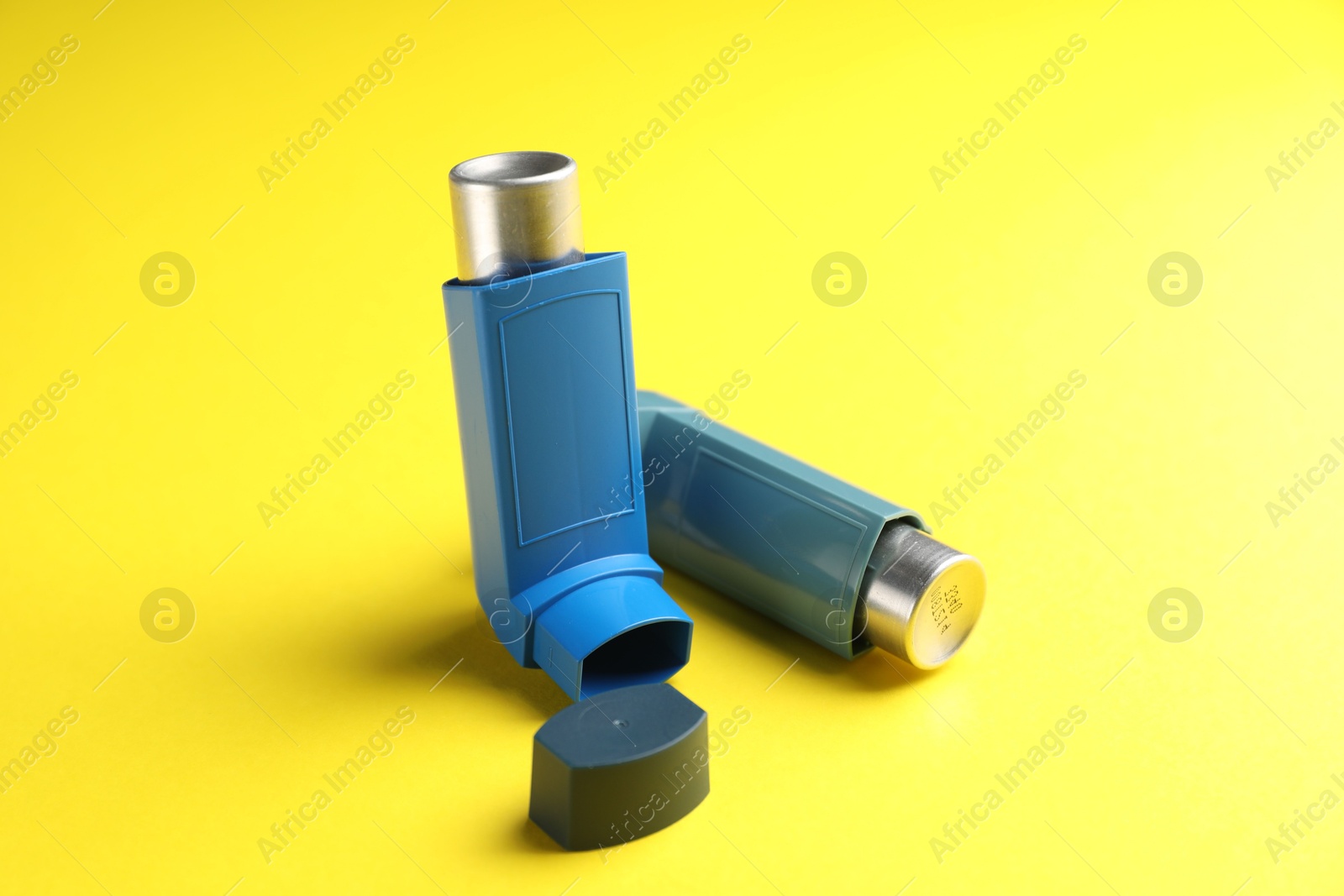 Photo of Respiratory problem. Two asthma inhalers on yellow background