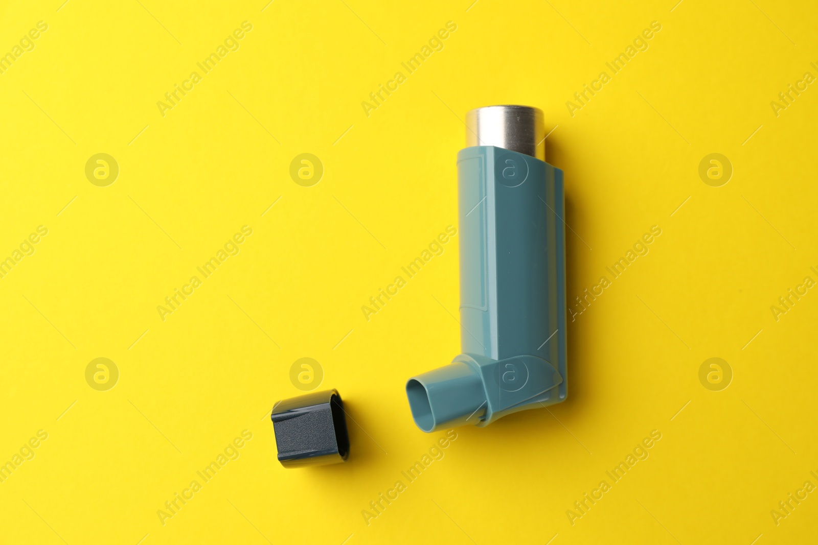 Photo of Asthma inhaler on yellow background, top view. Space for text