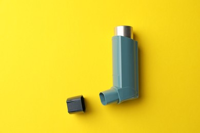 Photo of Asthma inhaler on yellow background, top view. Space for text