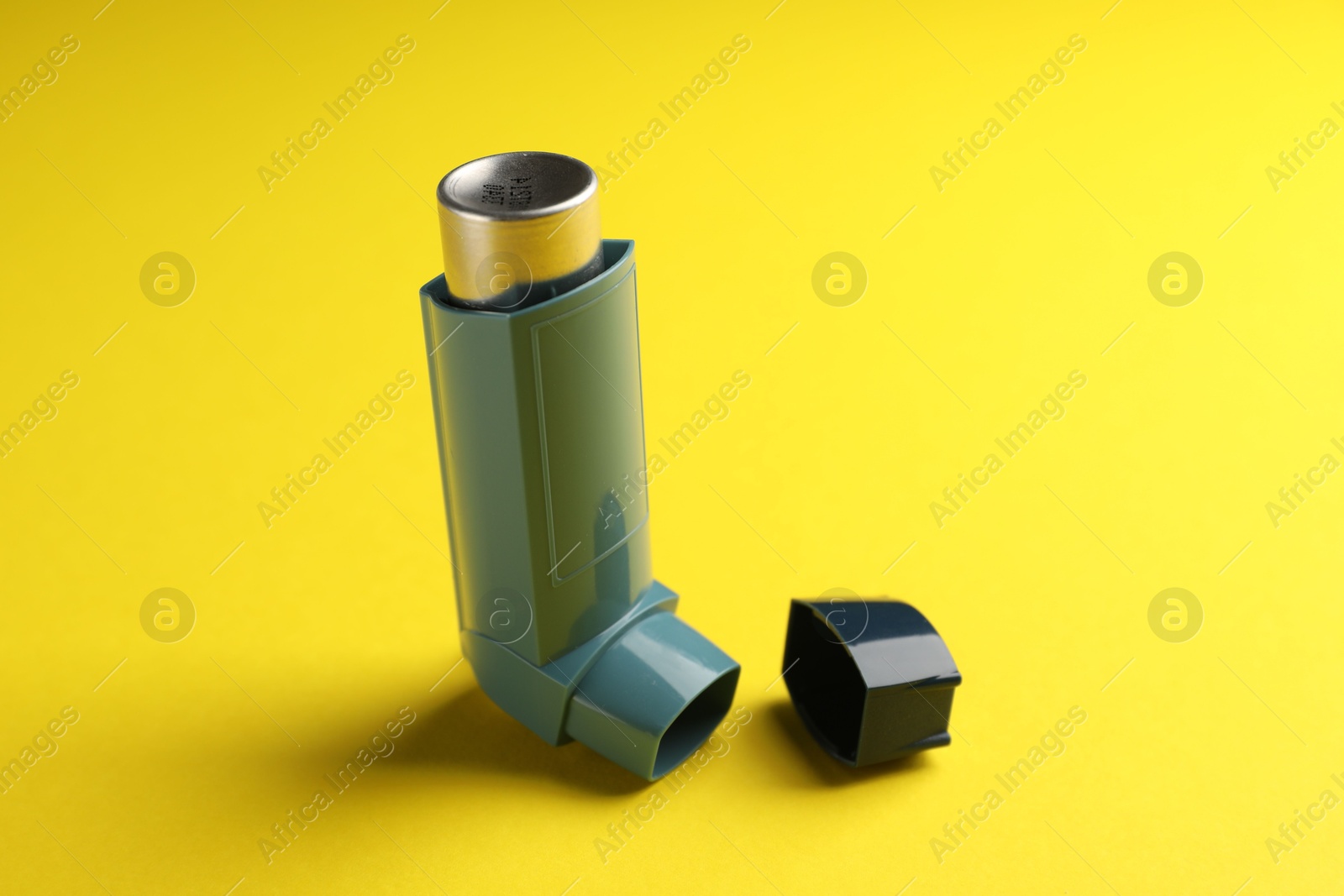 Photo of Respiratory problem. Asthma inhaler on yellow background