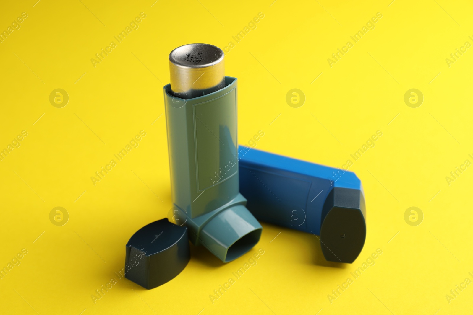 Photo of Respiratory problem. Two asthma inhalers on yellow background