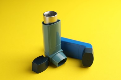 Photo of Respiratory problem. Two asthma inhalers on yellow background