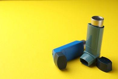 Photo of Two asthma inhalers on yellow background, space for text