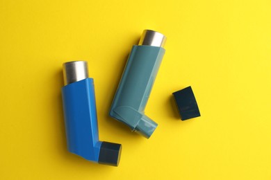 Photo of Two asthma inhalers on yellow background, top view