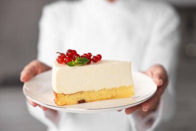 Photo of Professional chef with piece of delicious cheesecake in kitchen, closeup