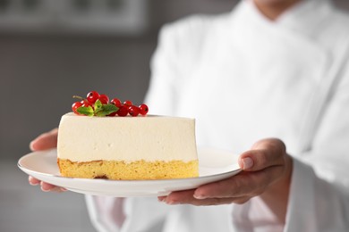 Professional chef with piece of delicious cheesecake in kitchen, closeup